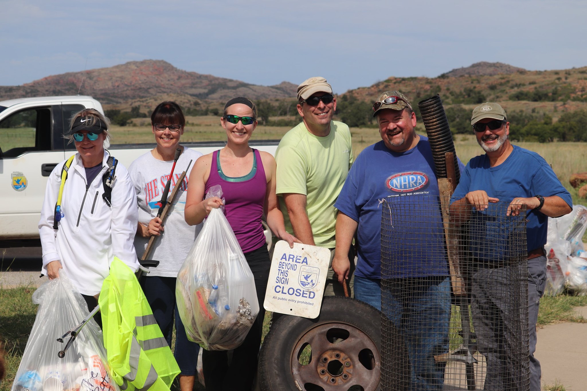 A group of volunteers stand together for a photo holding trash bags