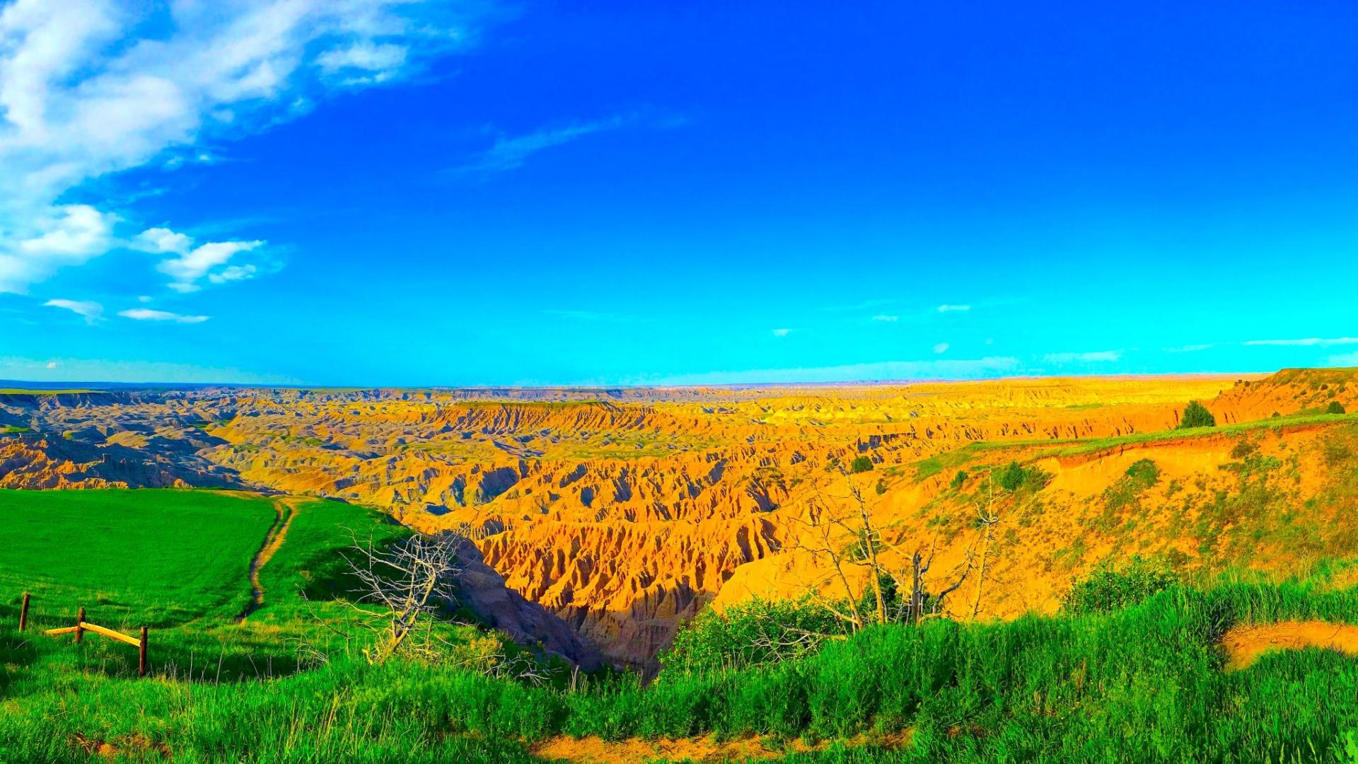 Photograph of a landscape of green and yellow hills against a blue sky.