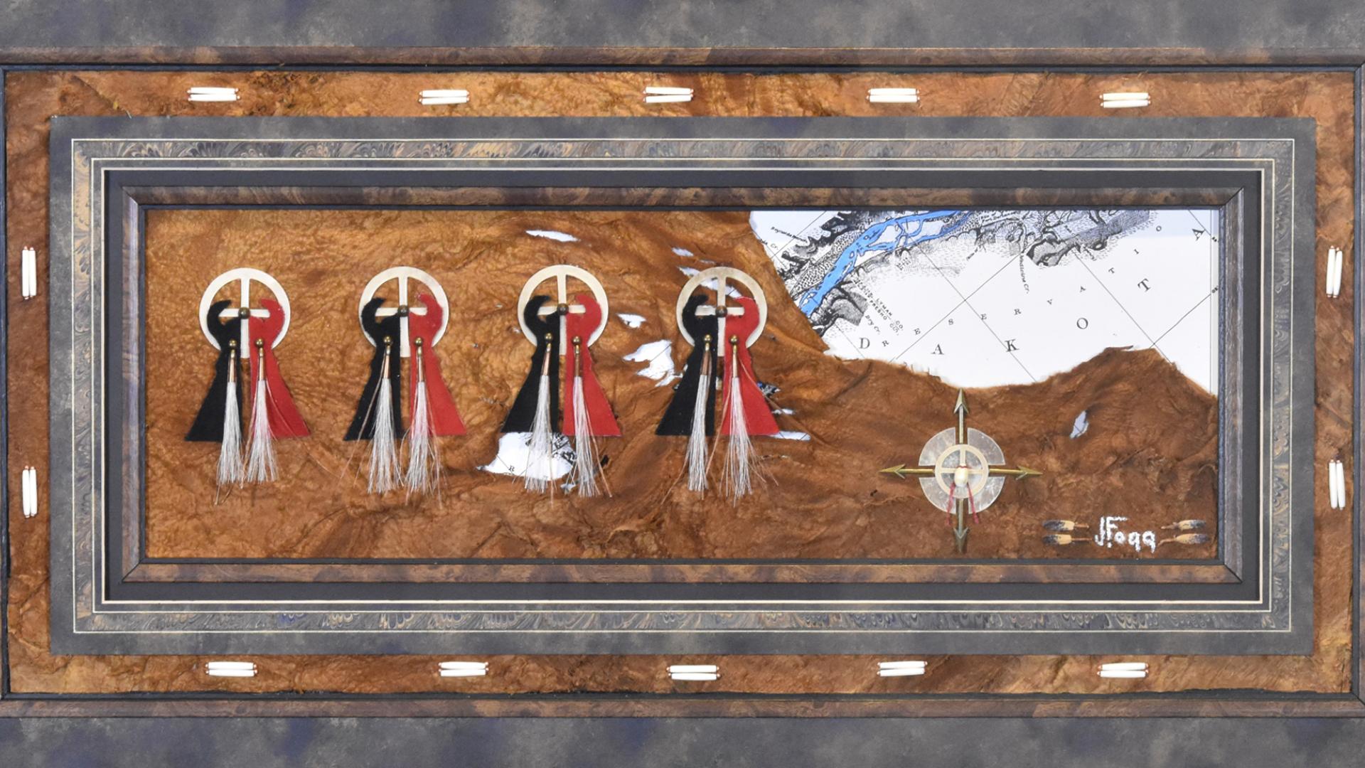 Four medicine wheels with ribbons on a hide laid over a map of the region of South/North Dakota.