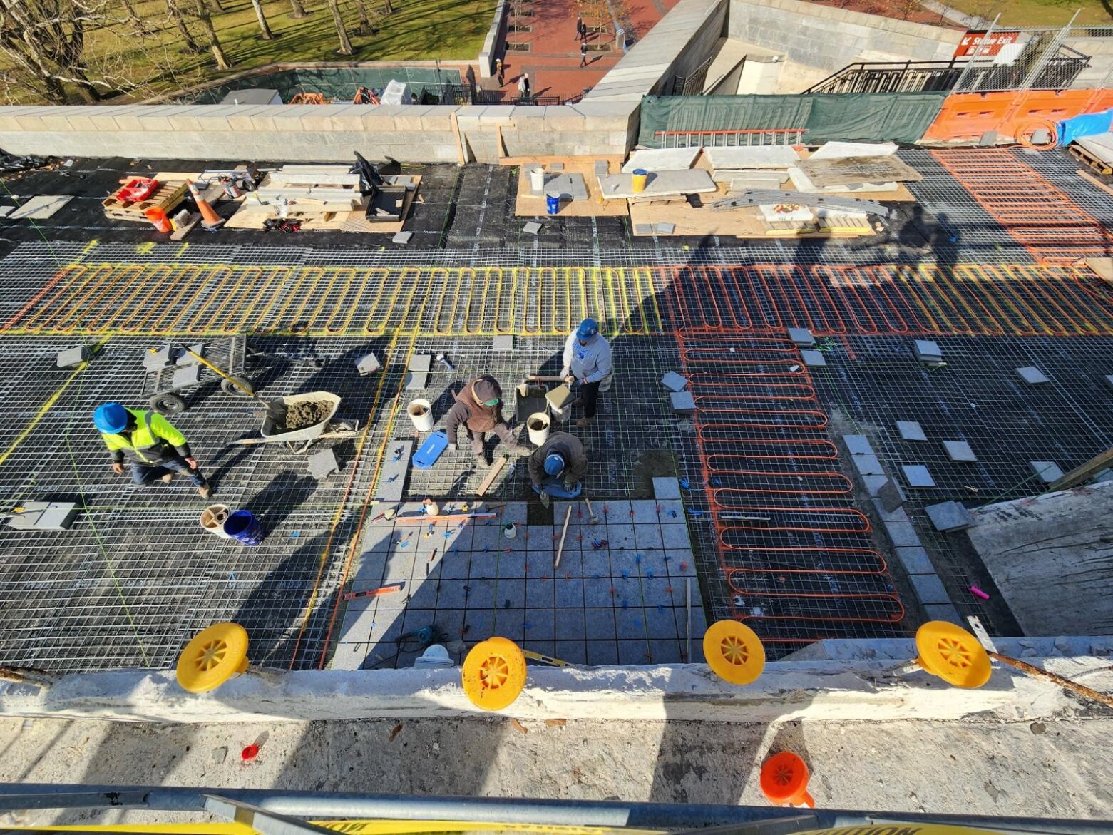 Aerial view of construction workers placing pavers on metal grating.