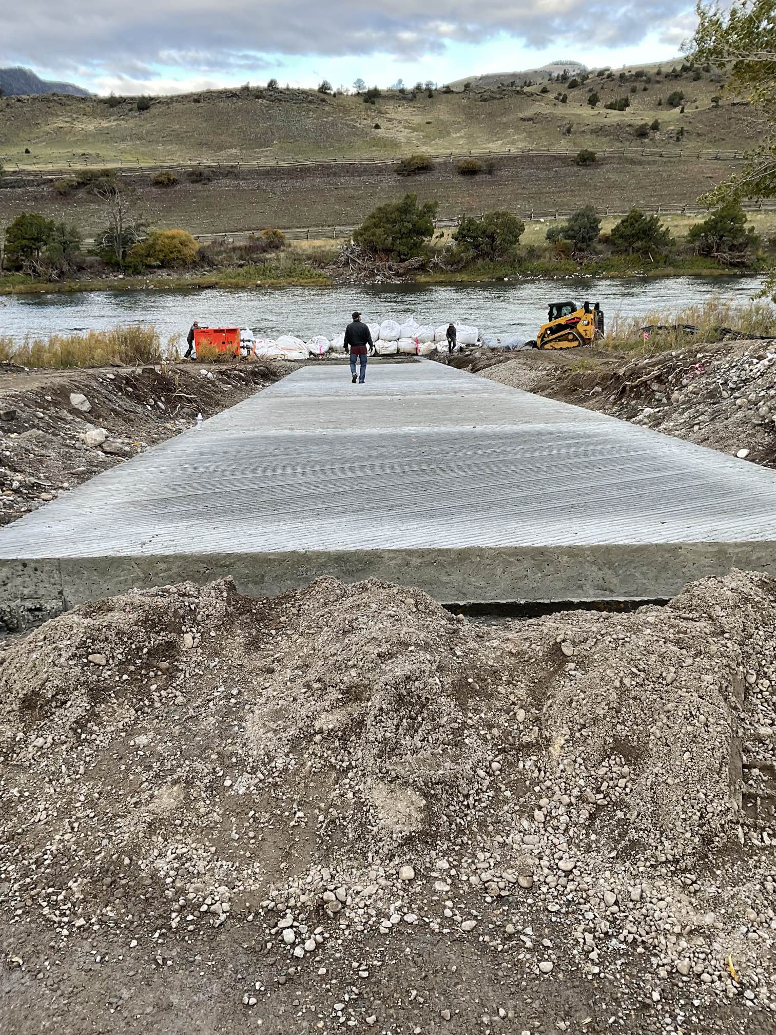 Man stands on new concrete boat launch surrounded by dirt mounds.
