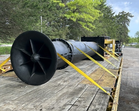 Pumping equipment piece secured to a long truck bed in transport. 