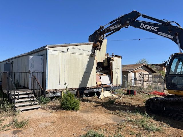 Excavator demolishes a building on a dirt plot at Hotevilla-Bacavi Community School.