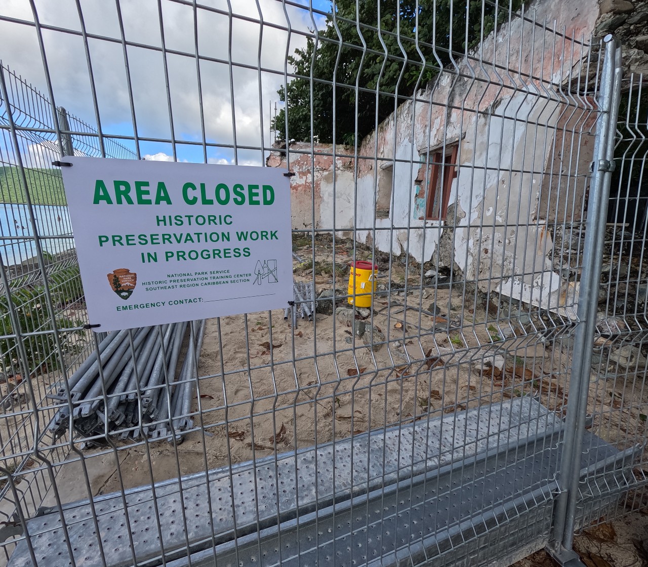 Image of the ruins at Cinnamon Bay surrounded by a fence with a sign that reads, Area Closed, Historic Preservation Work in Progress.