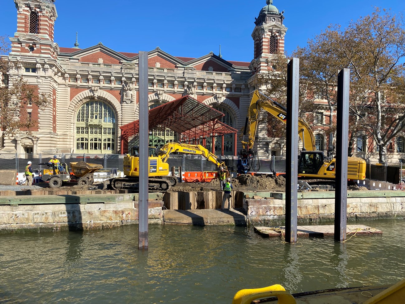 Heavy machinery dig into the ground in front of a large building.