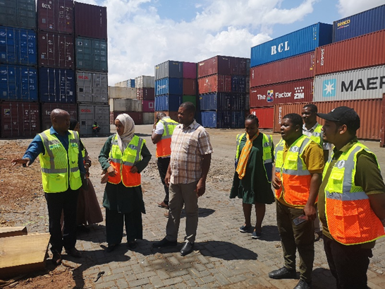 A group of Tanzanians stands at a shipping port learning about countering wildlife trafficking