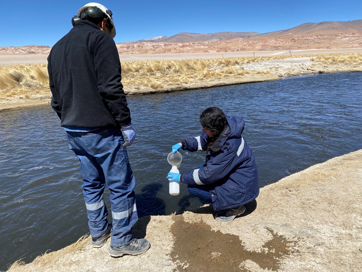 Two people on a river with a water bottle in work uniforms