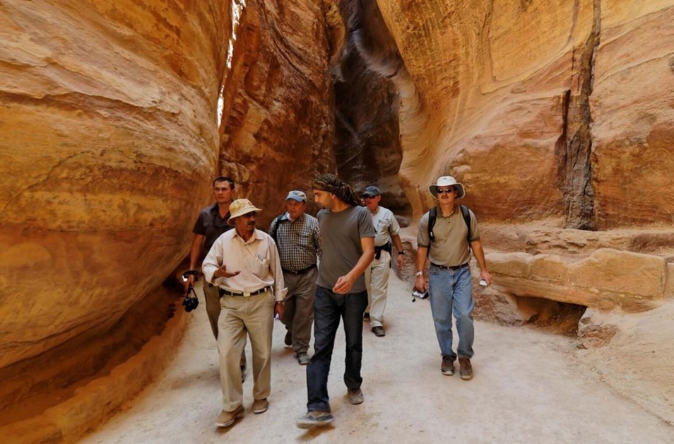 People walk through a passageway in large rock formations in Jordan