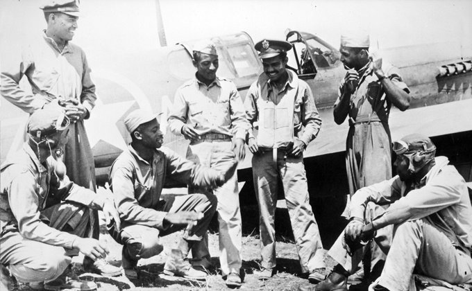 A black and white photo of seven Tuskegee Airmen planning for their mission over Anzio.