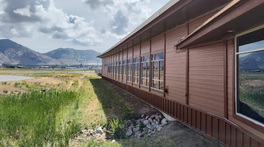 Exterior of one-story brown building with new siding.