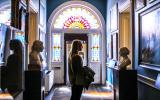 Visitor in a hallway with numerous paintings and busts of suffragists