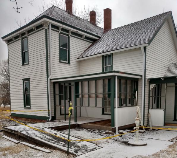 Farm House under construction covered in snow with yellow caution tape surrounding the entrance.