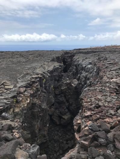 A large crack appears in the rocky ground