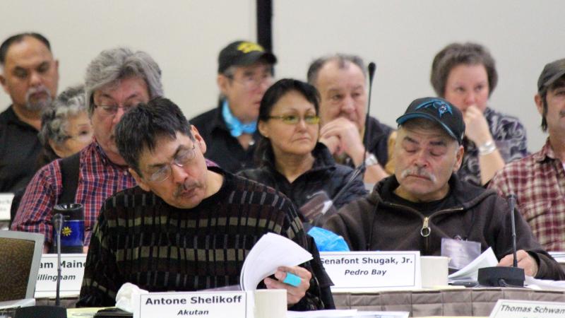 Council members sitting at a table listing and reading materials