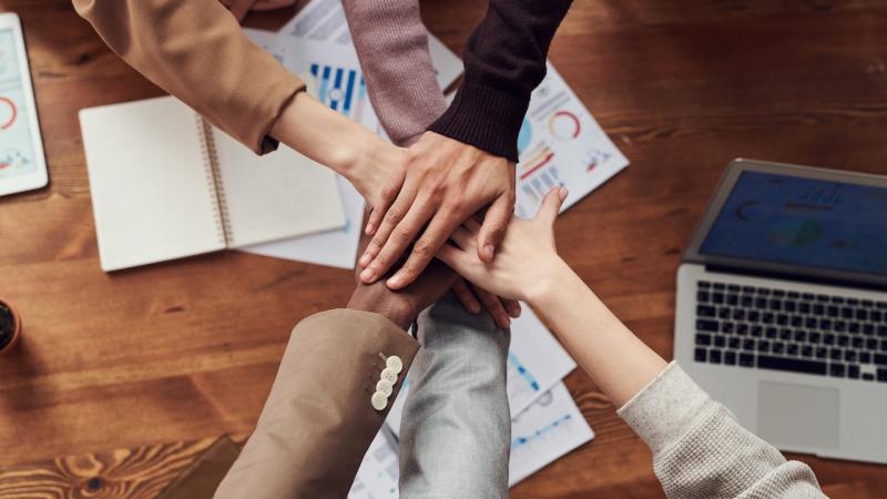 People putting their hands together in a teamwork gesture