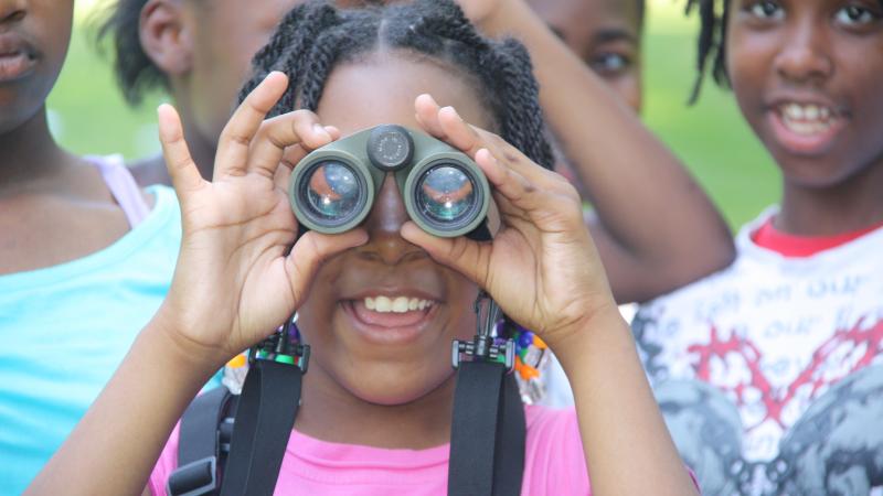 A young girl looks through binoculars