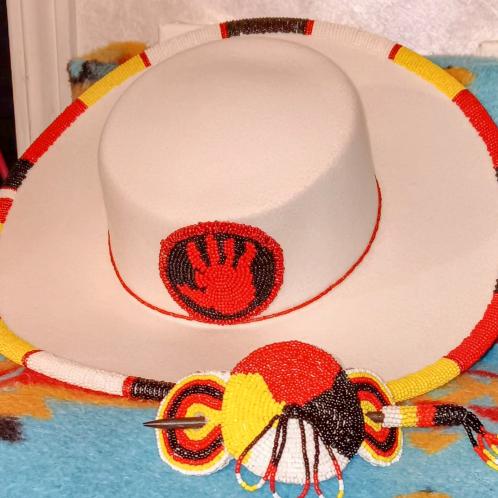 A tan hat with a beaded yellow, black, and red rim made by Deborah Buffalo.