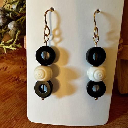 A pair of black and white dangling earrings.