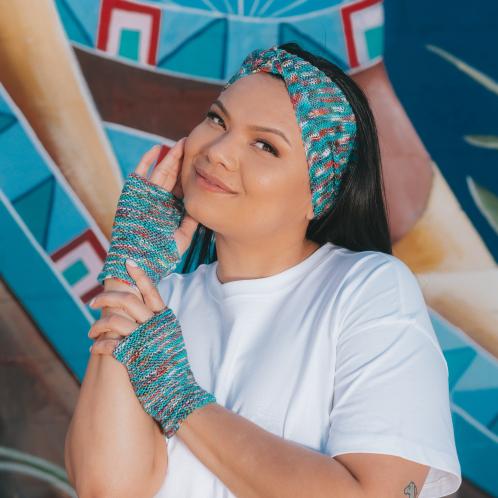 Photograph of woman posing wearing blue knitted hand warmers and a head band.