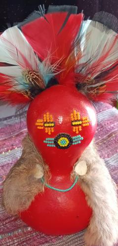 A red gourd doll with feathers decorating the head.