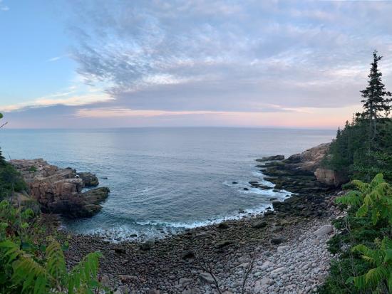 Waves crashing on shore of cobblestone beach at sunset.