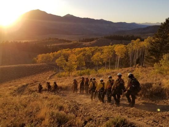 Hand crew walks toward the mountains at sunset.