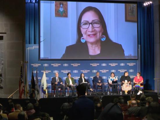 Secretary Haaland speaks to attendees on a large television screen at the White House Tribal Nations Summit