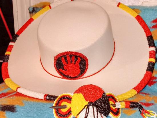A tan hat with a beaded yellow, black, and red rim made by Deborah Buffalo.