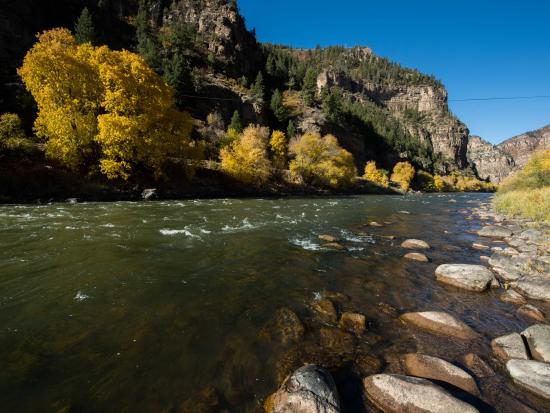 River moving through rocky area with yellowing Aspens along the rivers edge. 