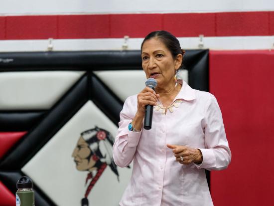 Secretary Haaland holding microphone speaking to audience during the Road to Healing Tour. 