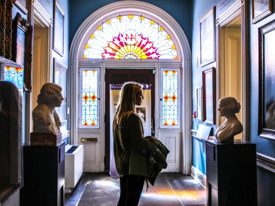 Visitor in a hallway with numerous paintings and busts of suffragists