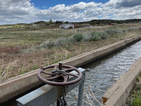 Irrigation canal running through grassy landscape.