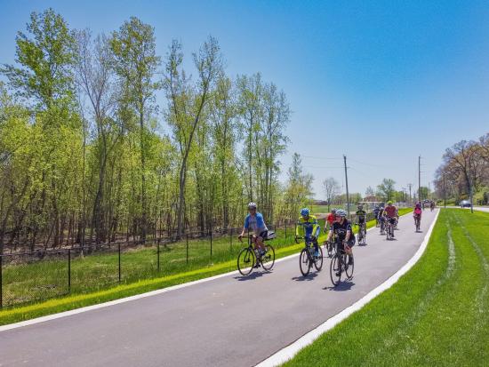 Group of bikers riding on paved bike path.