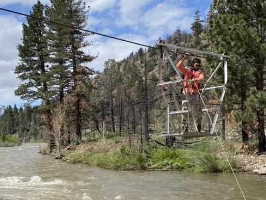 Hydro technician adjusting equipment over river. 