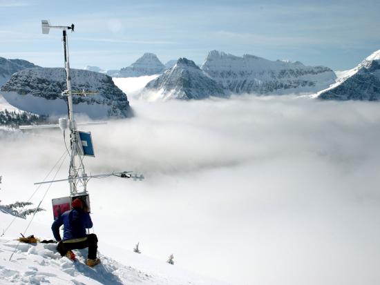 Scientist conducting research on snowy mountain landscape.