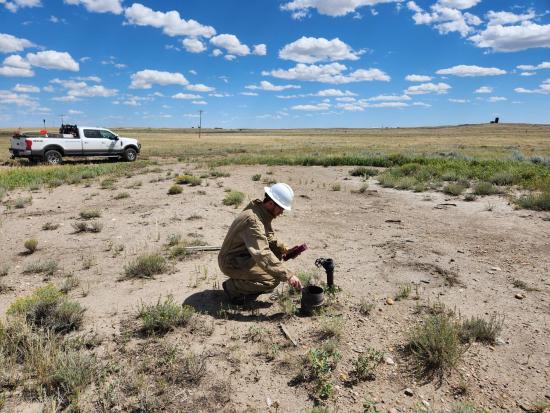 USGS employee testing an orphaned well in a dry field