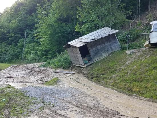 Wooden shed falling off hillside into muddy run off