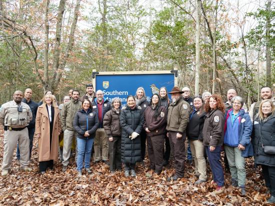 Secretary Haaland and group in front of Souther Maryland Woodlands National Wildlife Refuge Sign