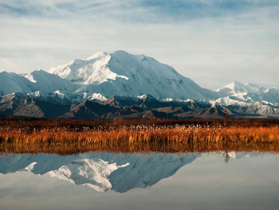 Snowy mountain reflected in body of water. 