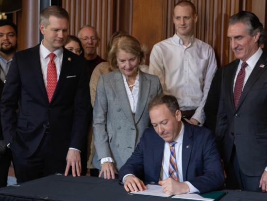 Secretary Burgum, Senator Shelley Moore Capito, Congressman Riley Moore and others in business attire stand behind EPA Administrator Lee Zeldin as he signs a document.