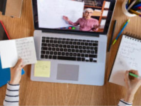 Image of desk with laptop, phone, notebook and womans hands. 