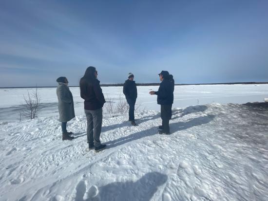 Five people stand together and talk in the snow