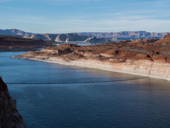 Lake Powell view from the top of the dam looking towards reservoir, surrounded by desert landscape. 