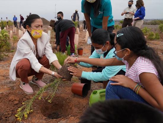 Secretary Haaland plants a tree alongside children at the San Diego Wildlife Refuge.