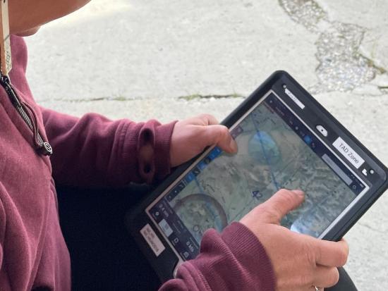 A wildland fire employee looks at a tablet with an aircraft application. 