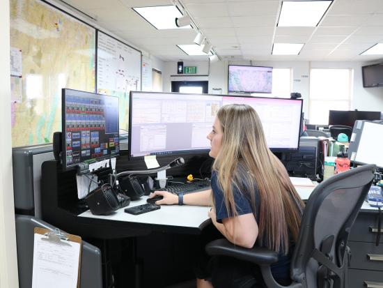 A dispatcher sits in front of computer screens as she uses dispatching programs to mobilize firefighters. 