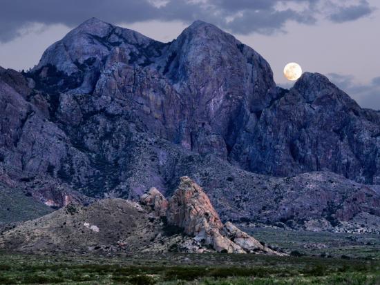 Moon behind blue mountain peaks. 