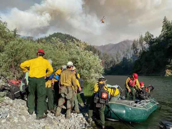 Wildland Firefighters wait by a river to be transported by boat to a nearby wildfire. 