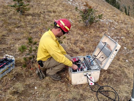 A firefighter sets up a radio system on an active wildfire. 