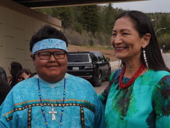 Secretary Haaland stands next to a young member of the Mescalero Apache Tribal community
